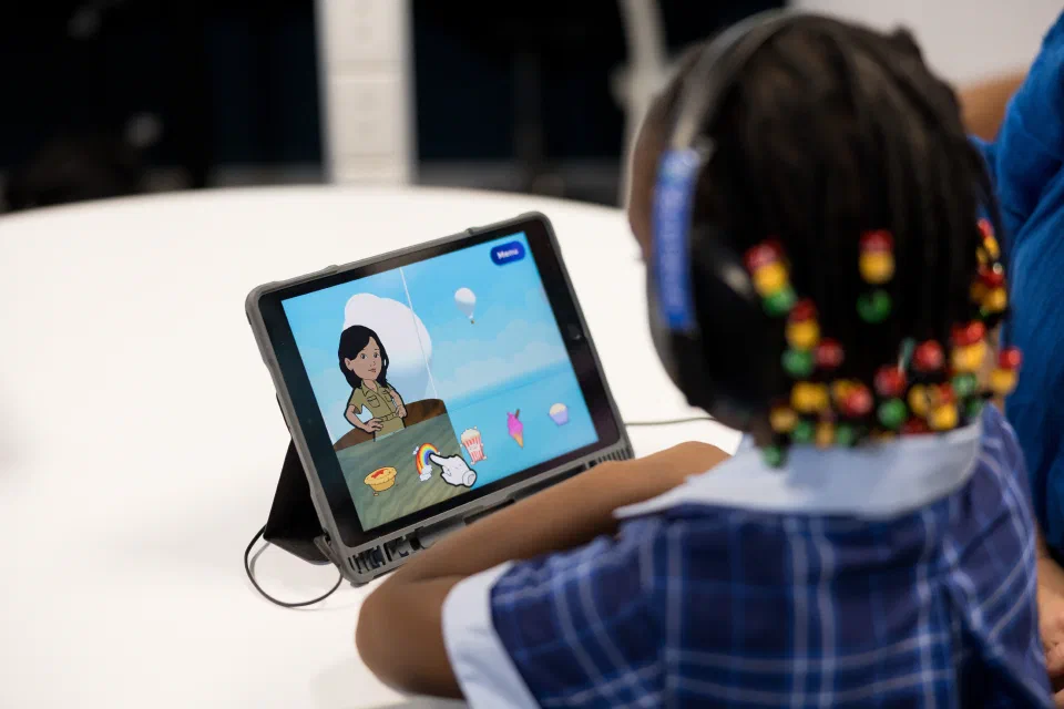 A child wearing headphones looking at an iPad open on the Sound Scouts app.