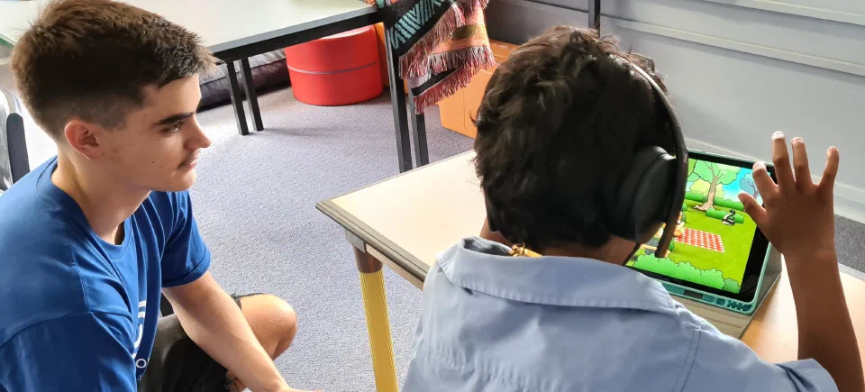Community health worker alongside a child completing a Sound Scouts hearing screen on a tablet.
