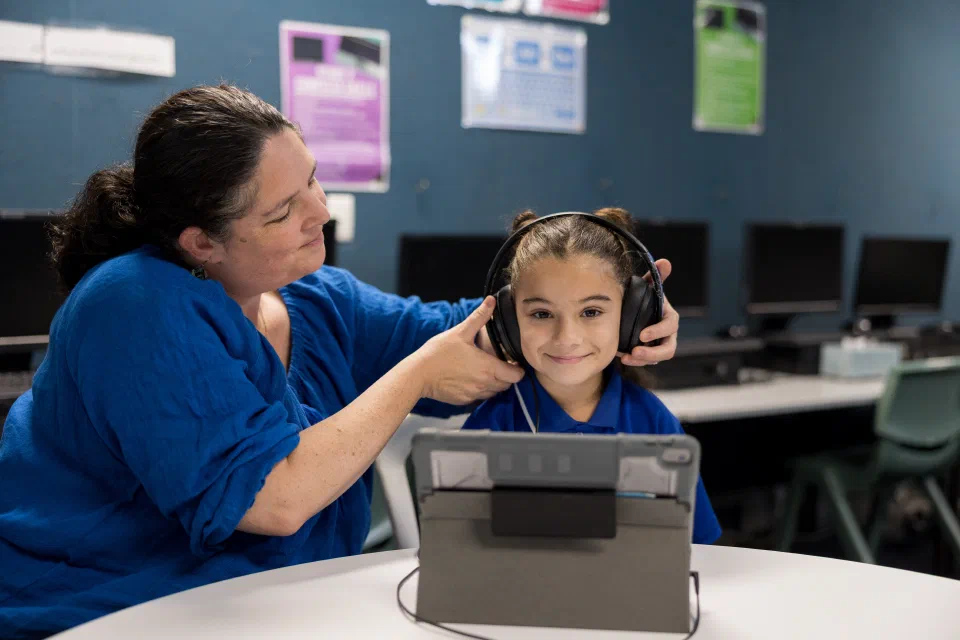 Health professional fitting headphones on a child as part of a school hearing screening