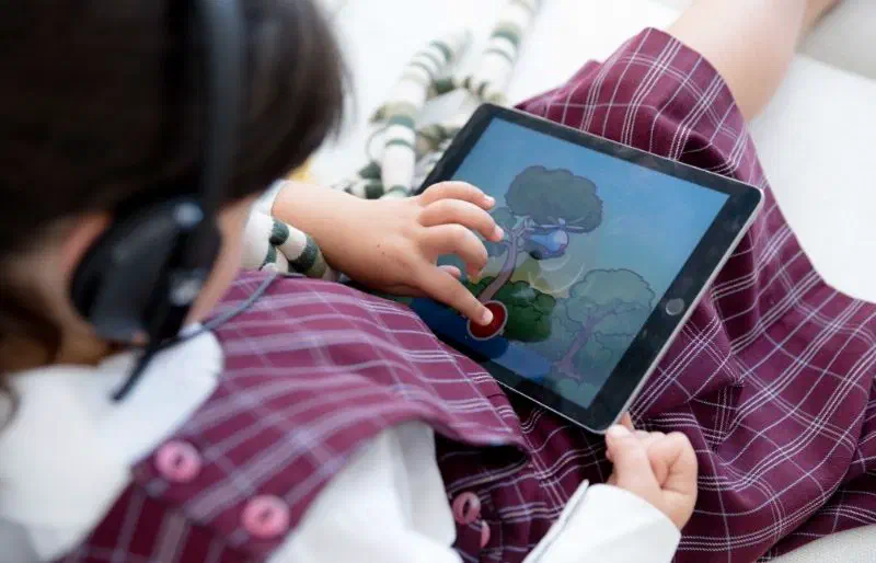 Over-the-shoulder shot of child in school uniform using the Sound Scouts gamified hearing test.