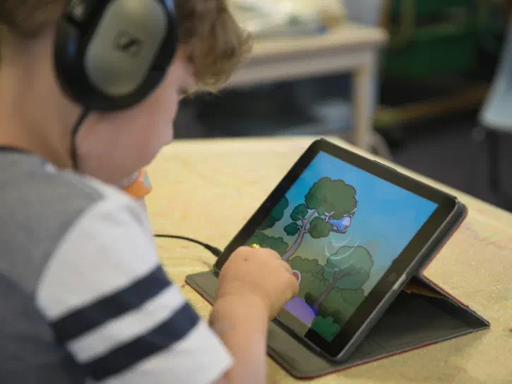 Child using Sound Scouts app on an iPad showing phonics test context