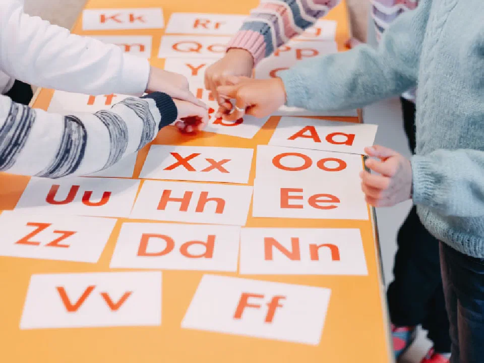 Children handling phonics cards laid out on a table