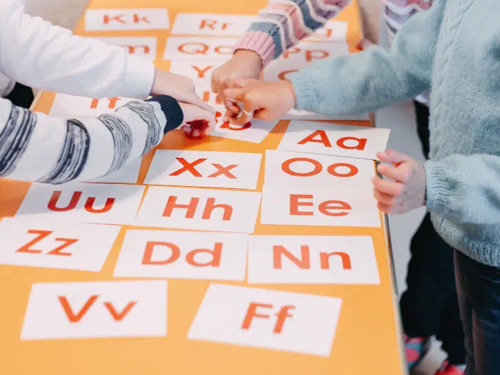 Children handling phonics cards laid out on a table